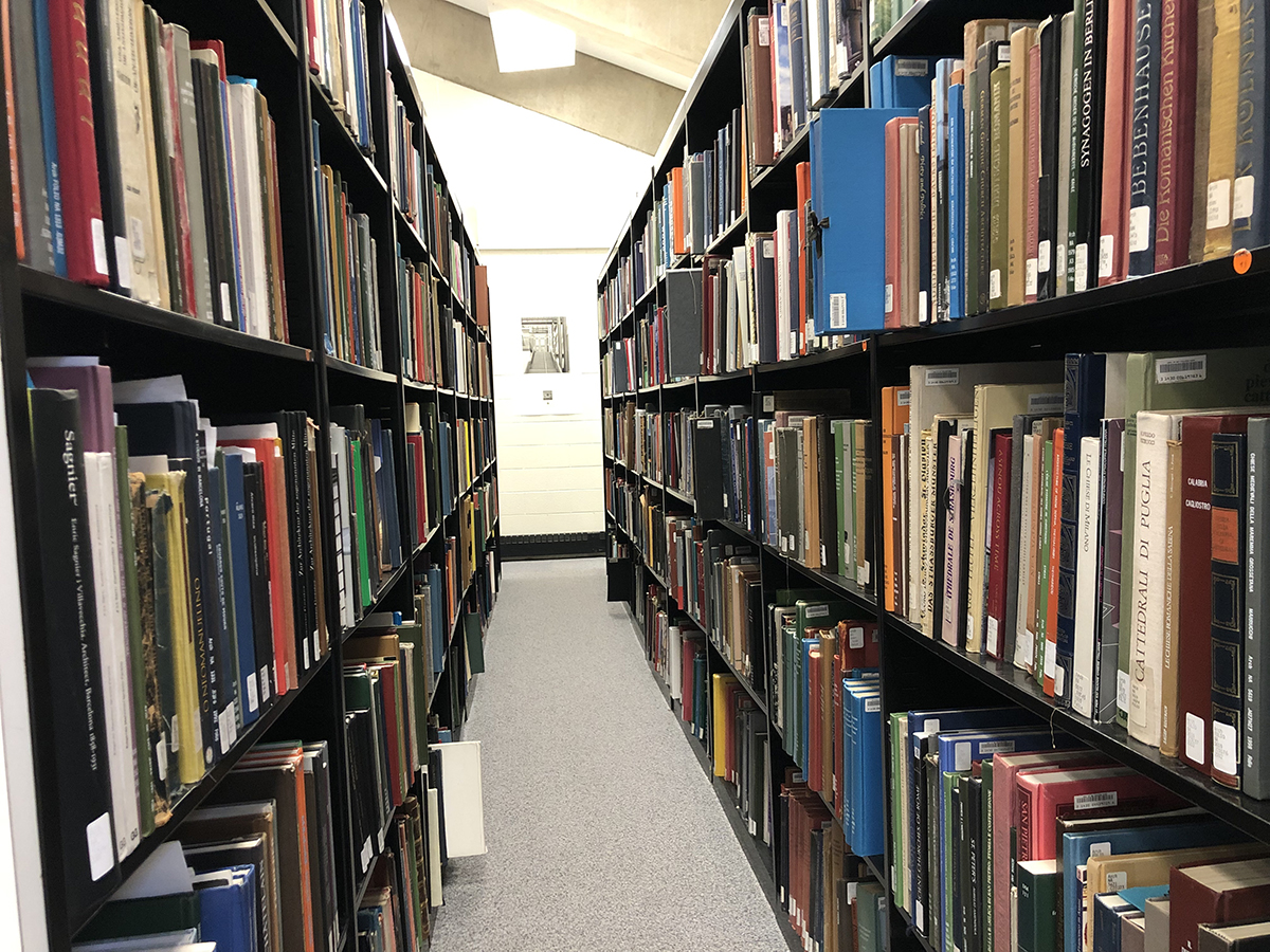 View down an aisle of bookshelves. The books are on both sides of the aisle.