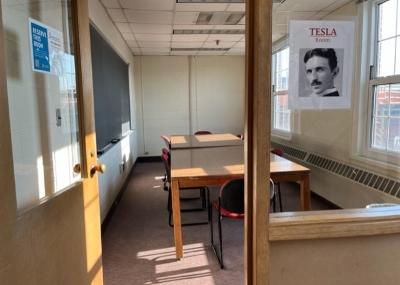 Sign with Nikola Tesla photo is displayed on window next to open door leading into the room